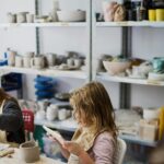 Young girl focused on crafting clay in a vibrant pottery workshop setting.