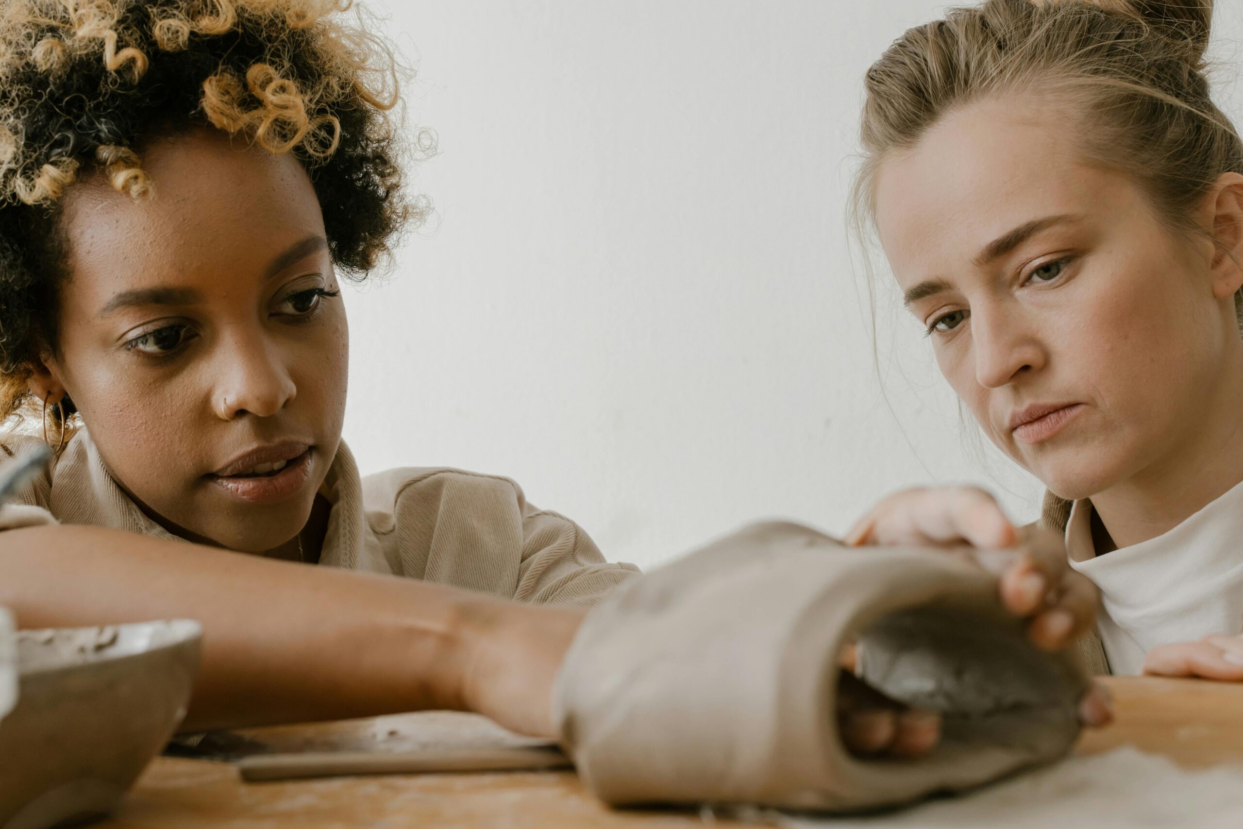 Two women focused on handcrafted clay pottery, showcasing their artistic skills.